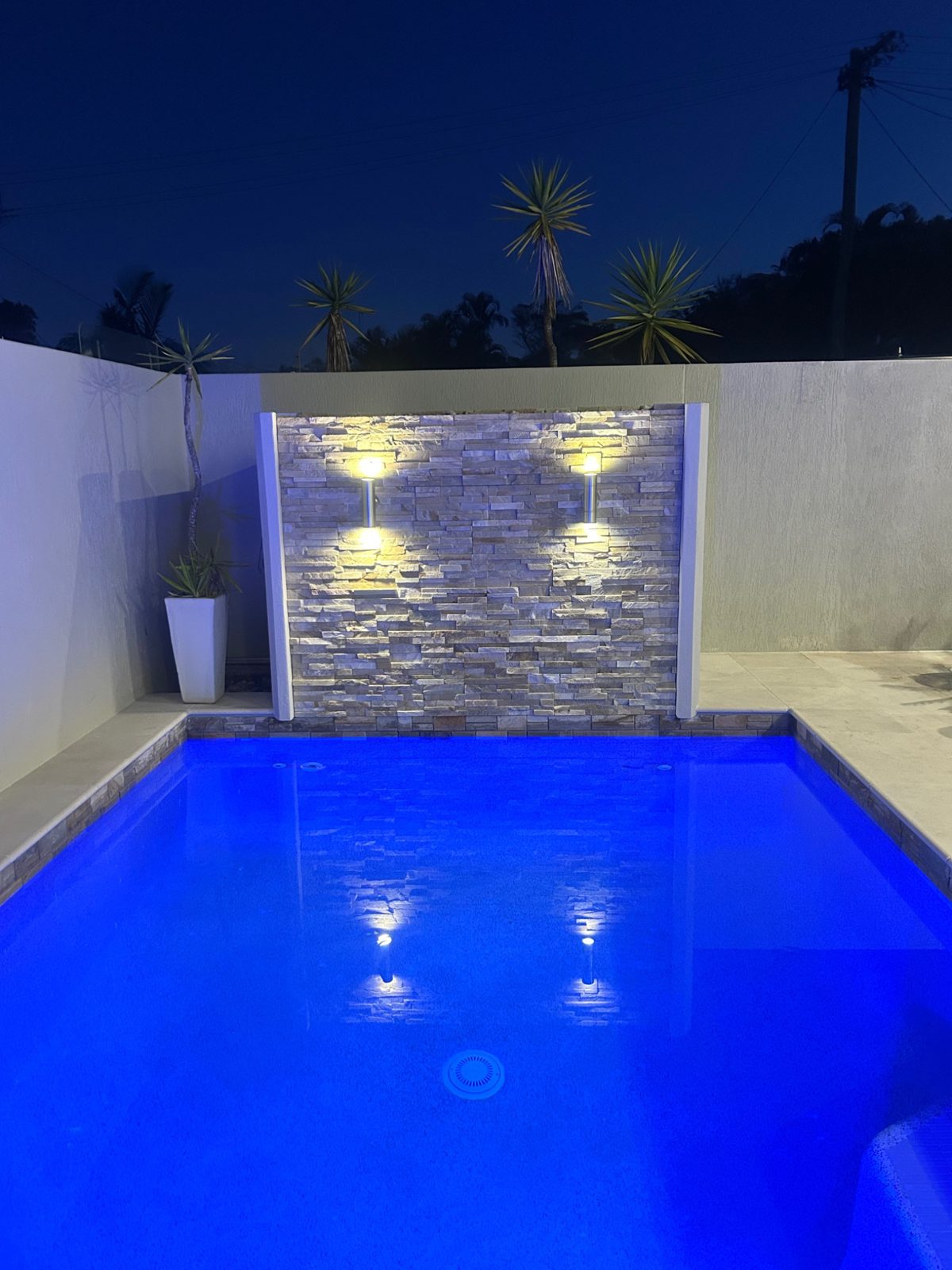 Illuminated stone feature wall by swimming pool